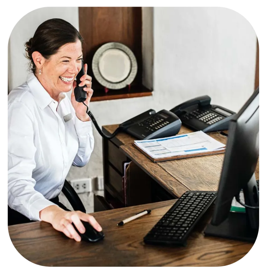 Recepcionista sonriendo mientras atiende el teléfono